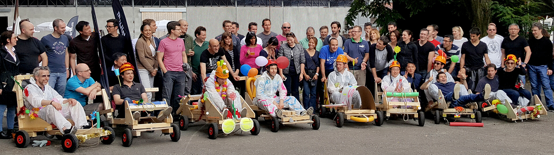 Menschen auf einem Parkplatz, in der ersten Reihe selbstgebaute Seifenkisten